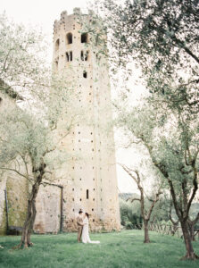 La Badia Di Orvieto destination wedding bride and groom walking in front ot tower