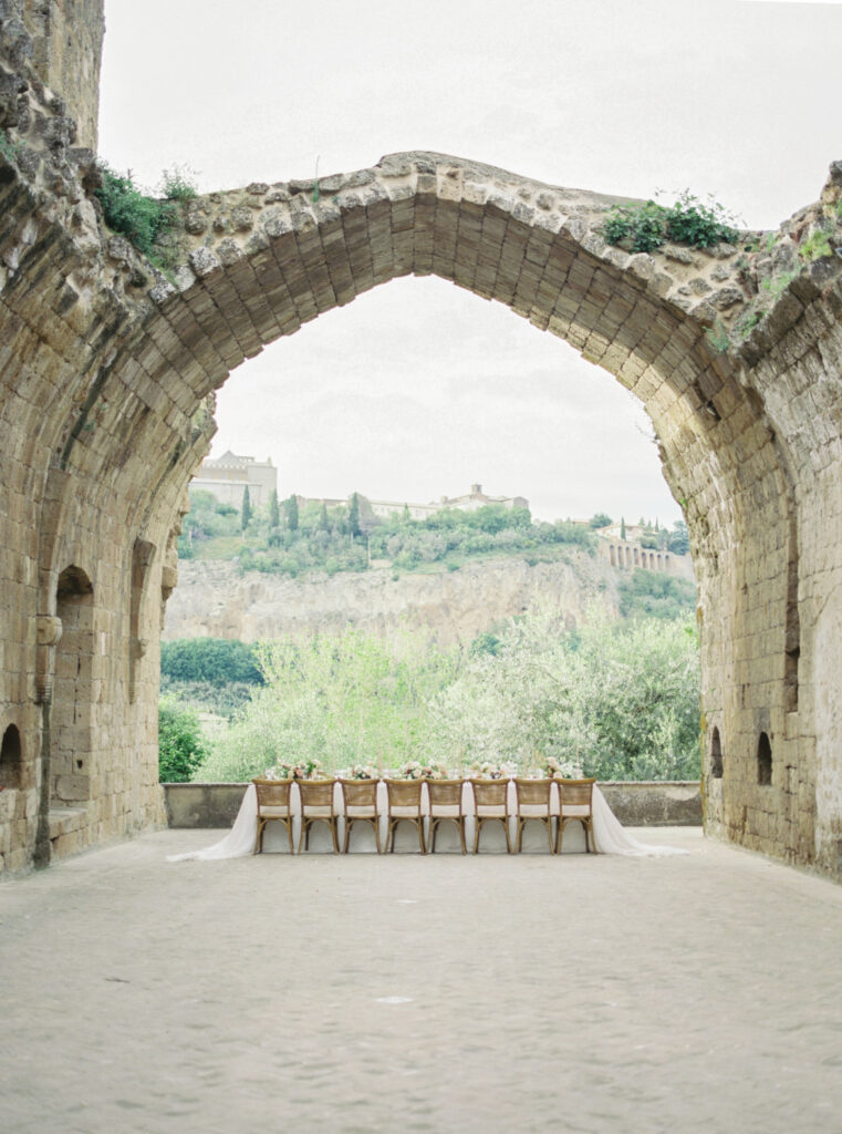 La Badia Orvieto in Italy reception set up under the ruins archway for an outdoor destination wedding reception