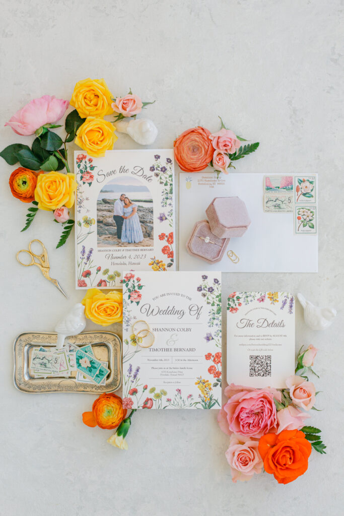 Garden Inspired wedding invitation with bright color roses, a mauve ring box with oval cut engagement ring and vintage stamps.