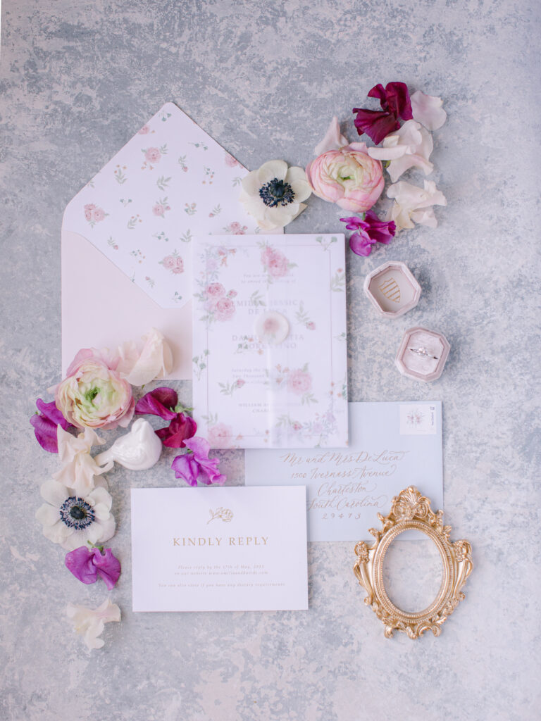 invitation suite with pink roses for a destination wedding in Charleston, SC and a pink mrs. box with white birds and a gold gilded frame on a painted backdrop.