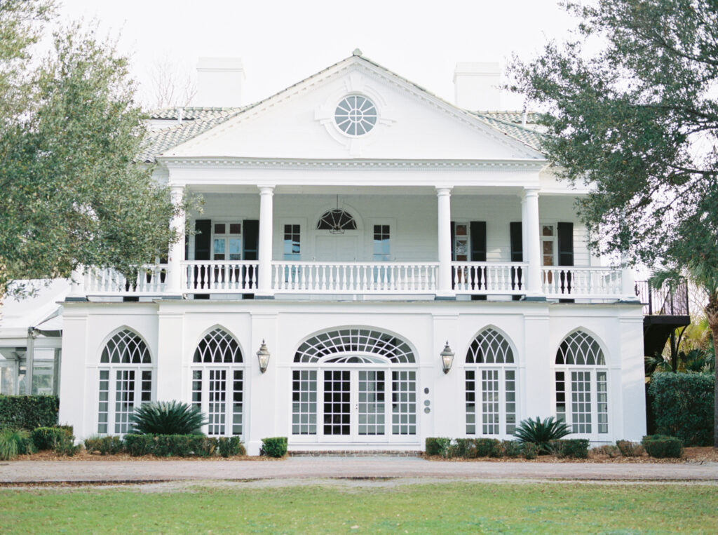 the main white house with columns and a lawn at lowndes grove estate