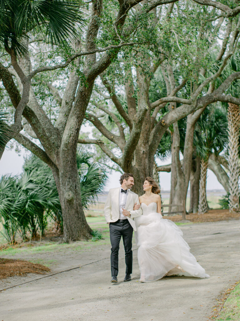 Bride and groom walking along a path at Lowndes Grove. Looking lovingly at each other on their wedding day. Wedding venue in charleston south carolina