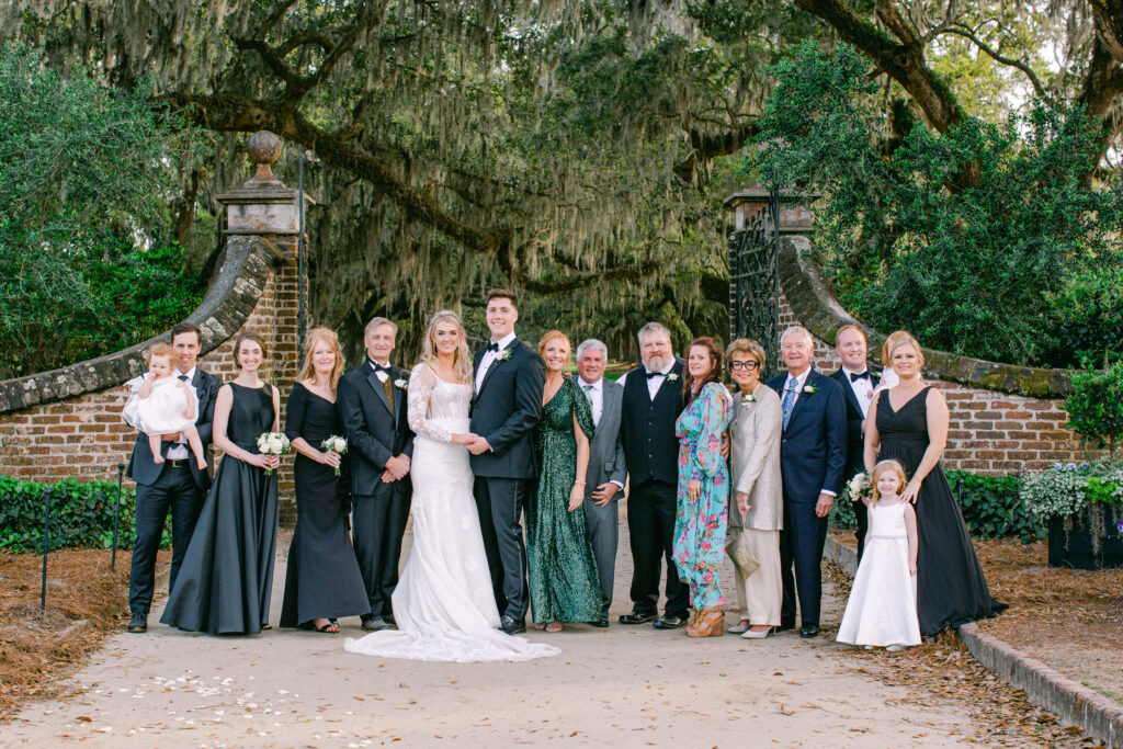 Family group picture with bridal couple at Boone Hall in front of the iron gate entrance. Boone Hall is located in Charleston, SC