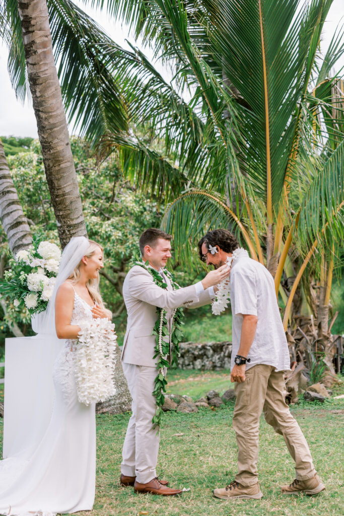 A man receiving a lei during a wedding ceremony at kualoa ranch in hawaii