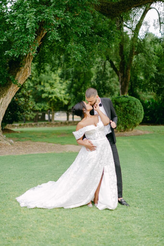 A Joyful Summer Wedding at a Private Estate in Raleigh, NC 3 Bride and Groom Kissing under a tree at a wedding venue in Raleigh North Carolina